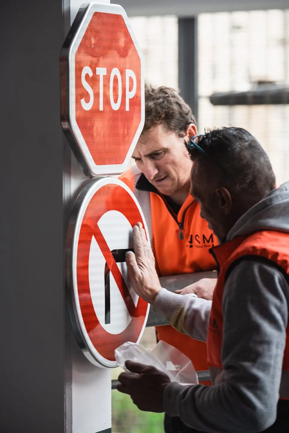 Deux salariés ASM contrôlant un panneau de signalisation en fabrication