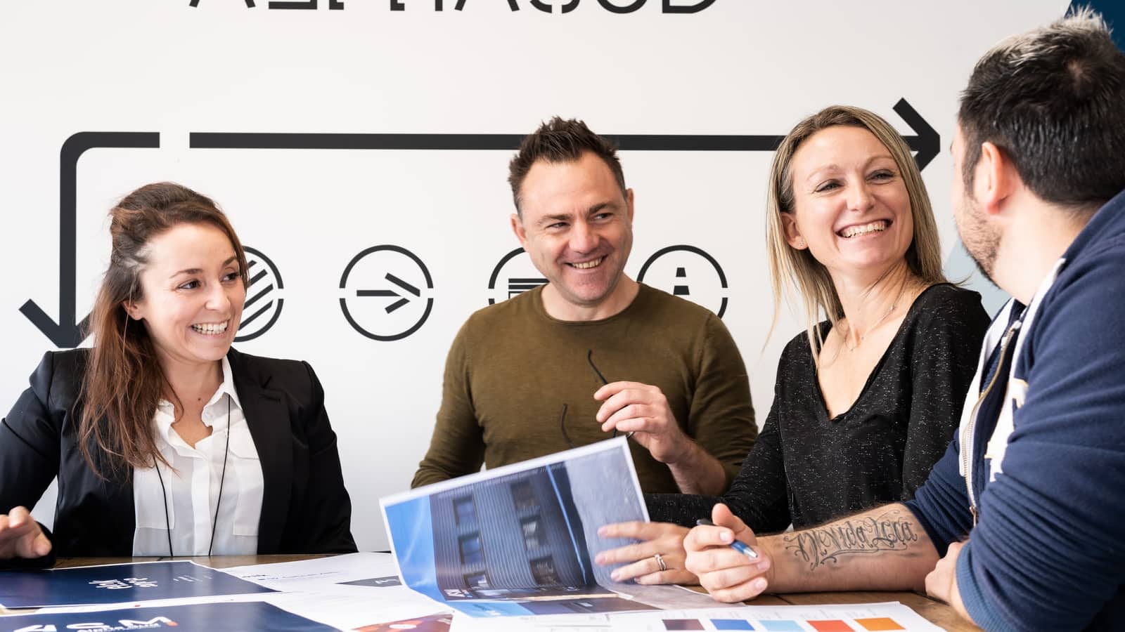 Équipe ASM réunie autour d'une table pour échanger sur un projet, plans et nuancier de couleurs posés devant eux