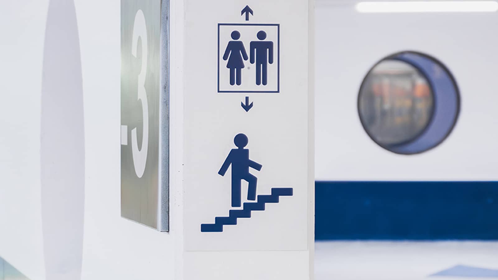 Pilier de parking avec numéro de niveau et pictogrammes d'orientation vers les sanitaires et les escaliers