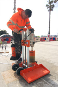 Technicien ASM utilisant une carotteuse pour percer le sol lors d’un chantier de préparation.