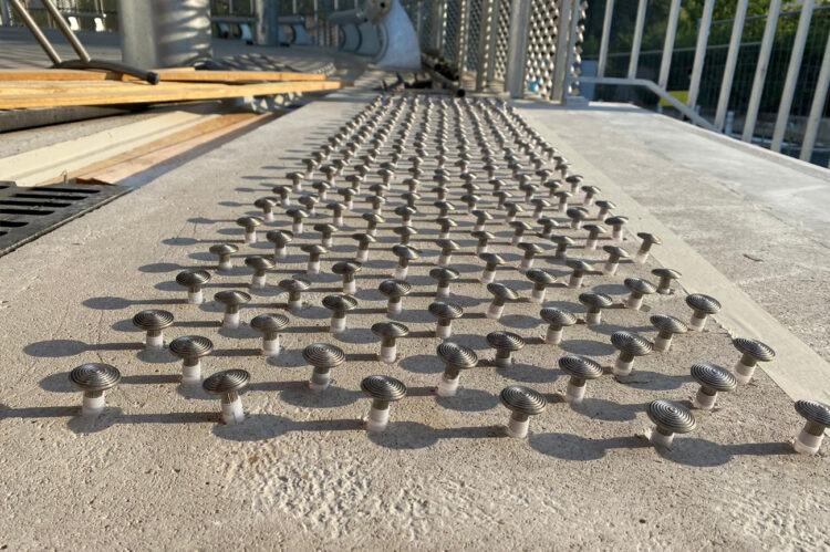 Clous podotactiles en inox posés sur une surface bétonnée pour guider les personnes malvoyantes.