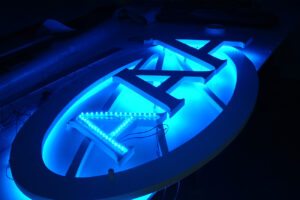 Fabrication d’une enseigne lumineuse rétroéclairée avec lettres découpées et éclairage LED bleu.