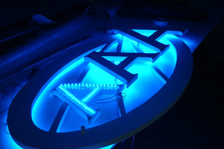 Fabrication d’une enseigne lumineuse rétroéclairée avec lettres découpées et éclairage LED bleu.