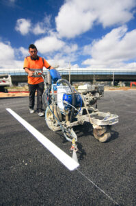 Marquage au sol de bandes de parking blanches réalisé avec une machine traceuse professionnelle.