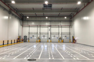 Marquage au sol et signalétique dans un entrepôt logistique avec bandes de circulation et zones de quai.