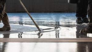 Travaux d’application de résine de sol industriel par ASM, avec lissage manuel et utilisation de chaussures à pointes, en région PACA