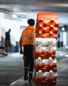 Agent ASM en gilet de sécurité manipulant des barrières modulables rouges et blanches pour le balisage d’un chantier dans un parking en région PACA.