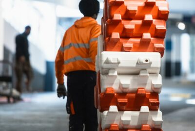 Agent ASM en gilet de sécurité manipulant des barrières modulables rouges et blanches pour le balisage d’un chantier dans un parking en région PACA.