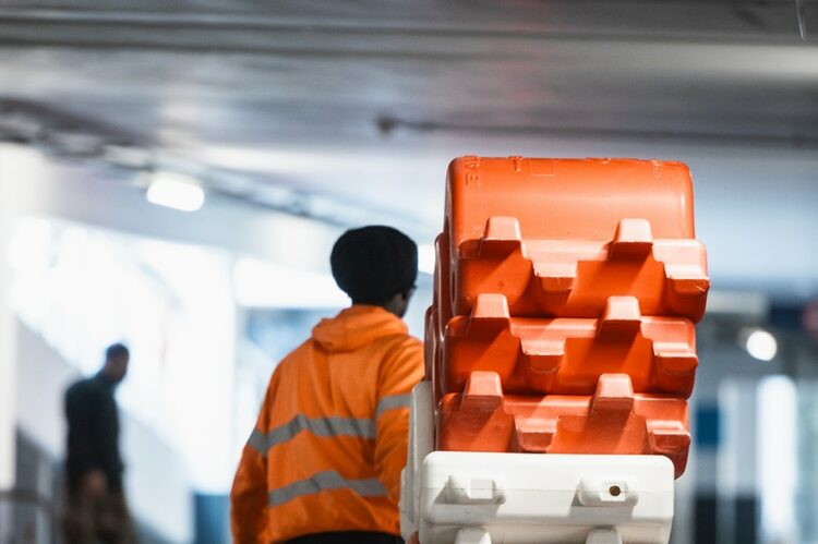 Agent ASM en gilet de sécurité manipulant des barrières modulables rouges et blanches pour le balisage d’un chantier dans un parking en région PACA.