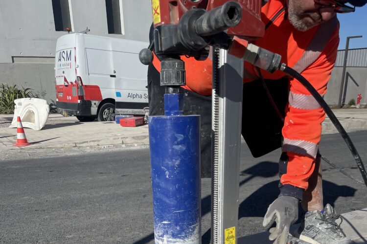 Technicien ASM utilisant une carotteuse pour préparer le sol avant la pose de potelets de sécurité urbains.