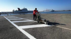 Opérateur ASM effectuant un marquage au sol portuaire à la Ciotat avec des lignes blanches durables