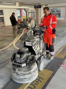 Techniciens ASM utilisant une surfaceuse pour préparer le sol d’un parking avant application de résine.