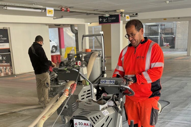 Techniciens ASM utilisant une surfaceuse pour préparer le sol d’un parking avant application de résine.