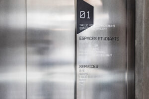 Signalétique verticale intérieure sur mesure indiquant les espaces étudiants et services d’un bâtiment.